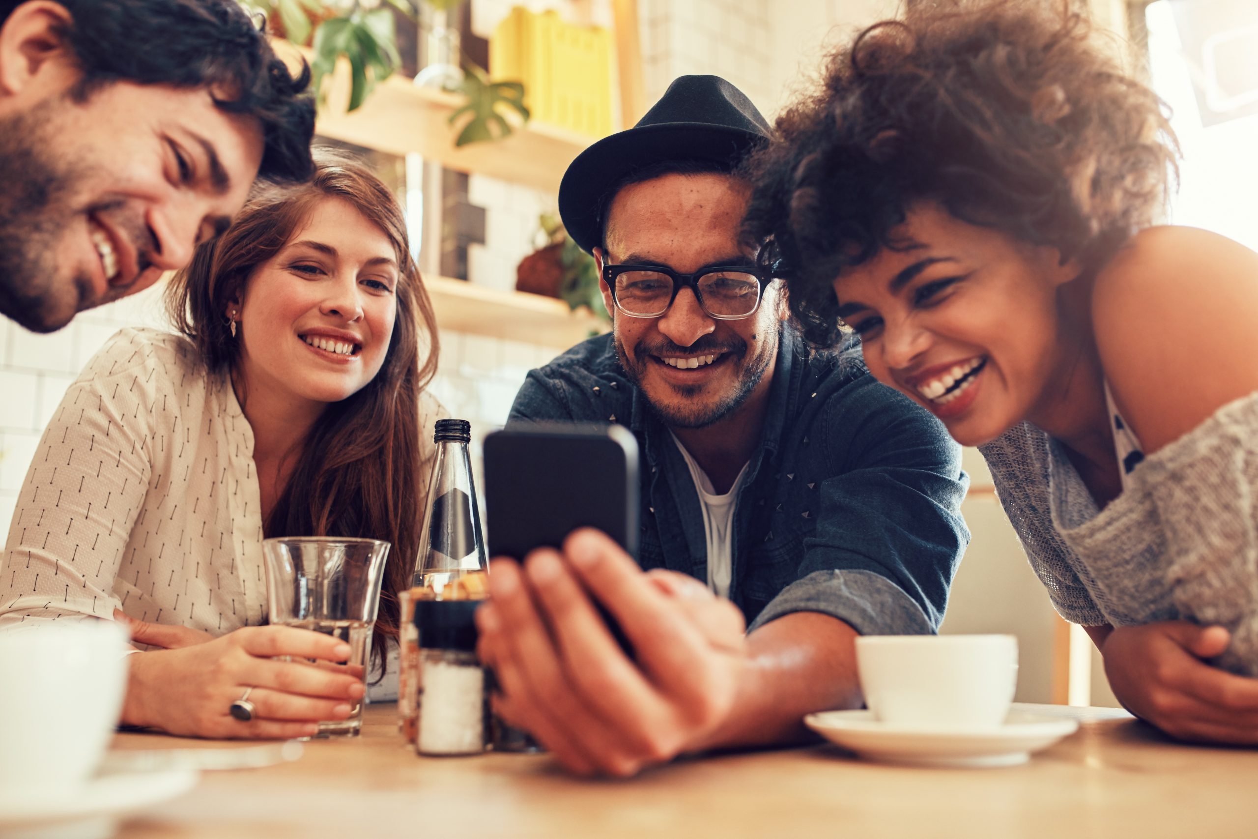 Group of friends sitting together in a cafe looking at mobile phone