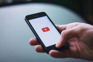 Close-up of a hand holding a smartphone displaying the YouTube app on the screen