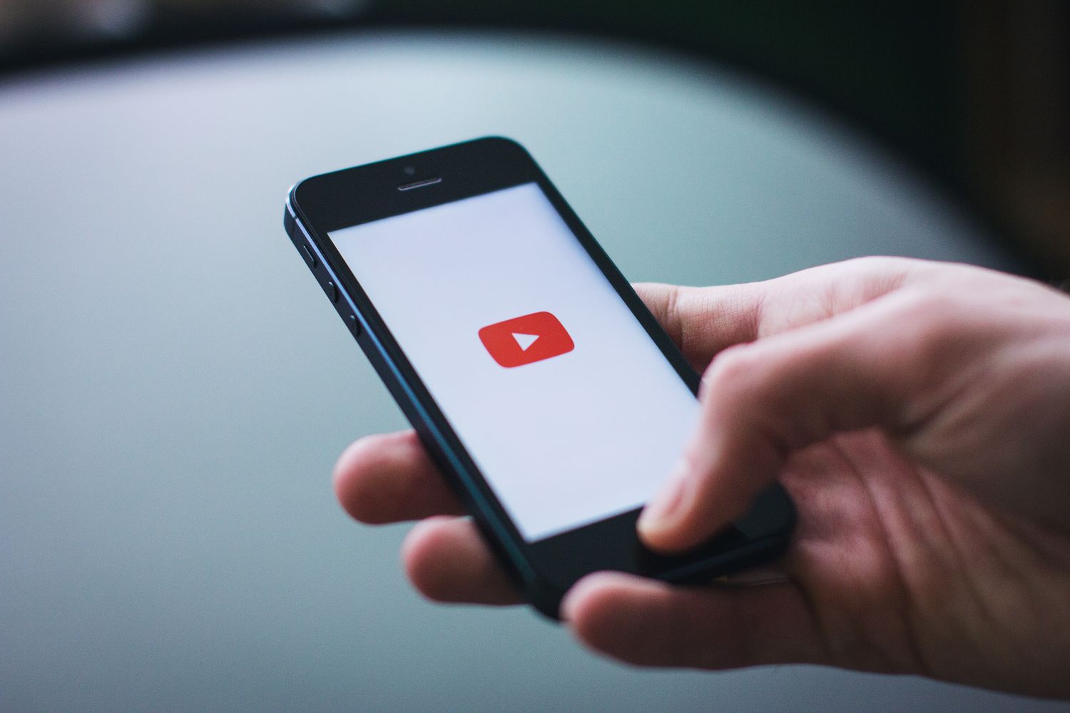Close-up of a hand holding a smartphone displaying the YouTube app on the screen